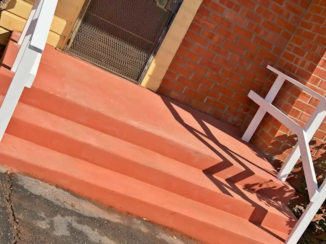 Terracotta-colored concrete front steps with white handrails at a yellow-sided home entry, labeled "After"