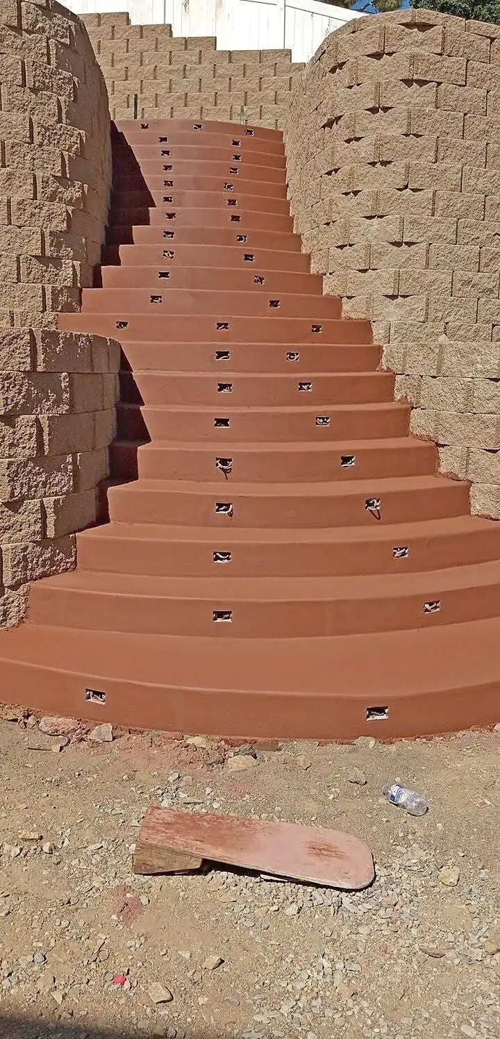 Curved terracotta-colored concrete stairway between split-face block retaining walls