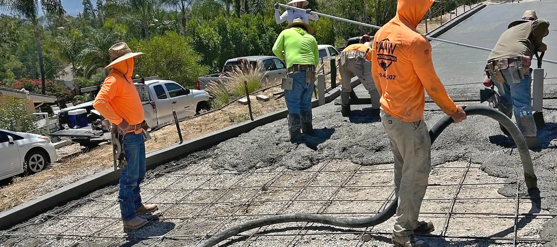 Raaw Concrete Inc. crew pumping and spreading concrete over rebar grid on sloped residential driveway