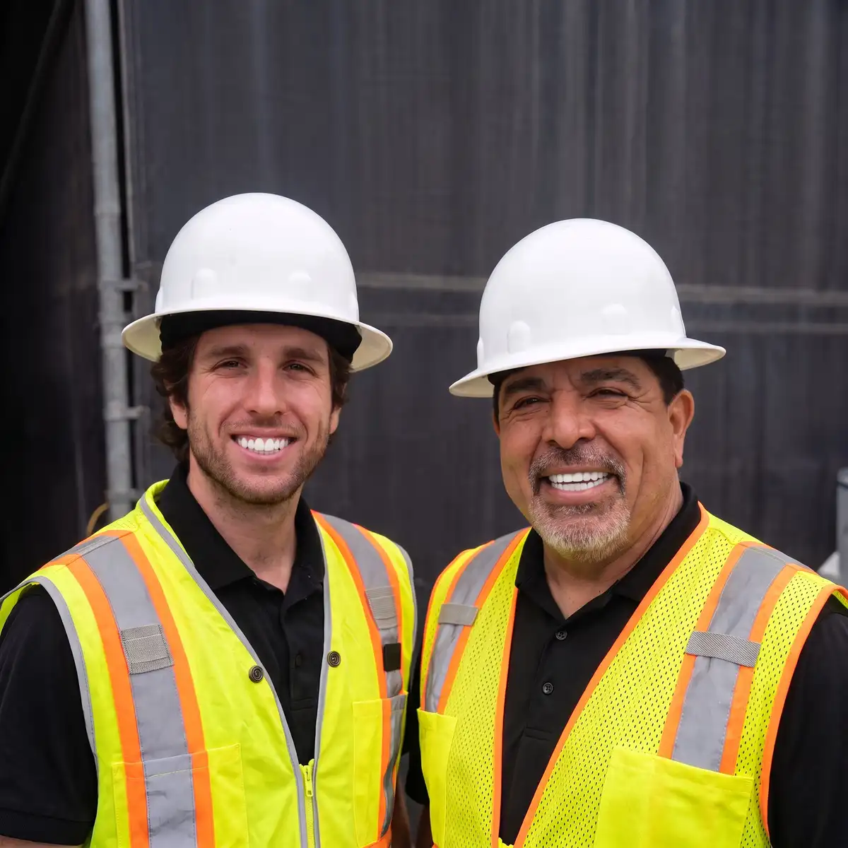 Willie Dupleich and his son Ryan Dupleich in hard hats and high-visibility vests on a concrete job site